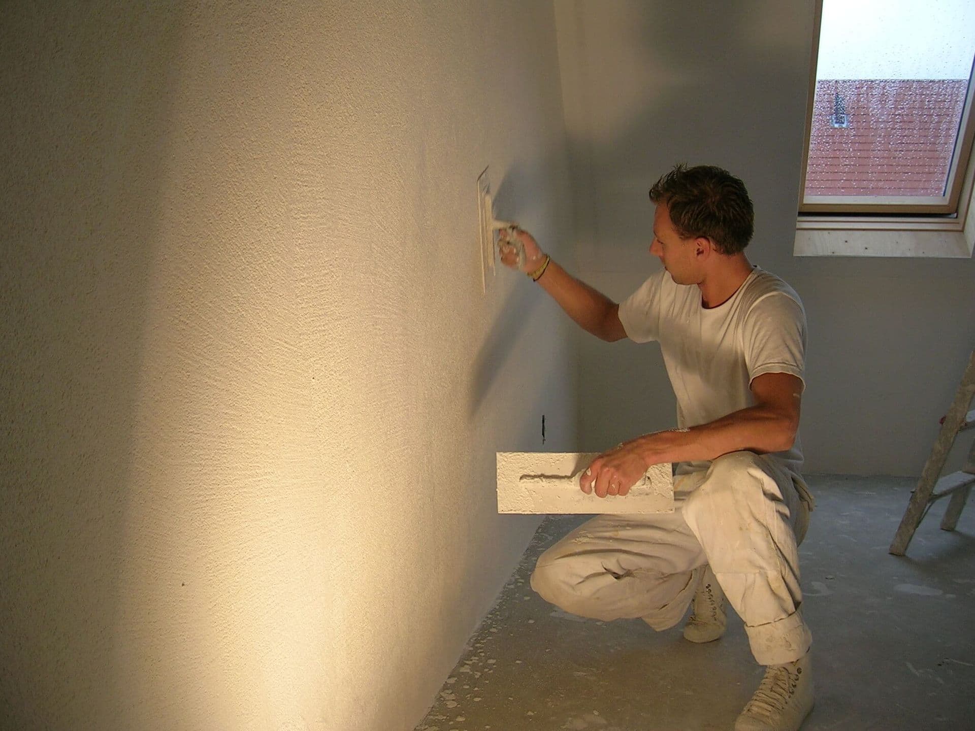 Stukadoor brengt glad stucwerk aan op een wand